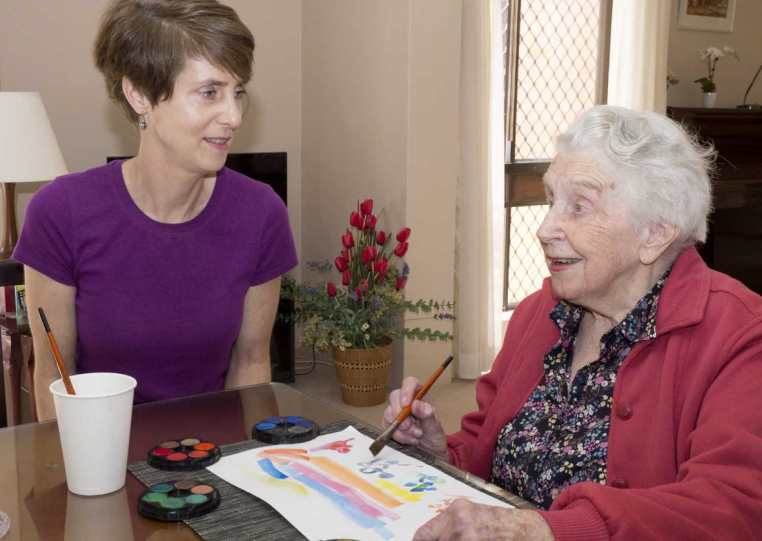 An elderly woman engaging in art therapy with an art therapist.