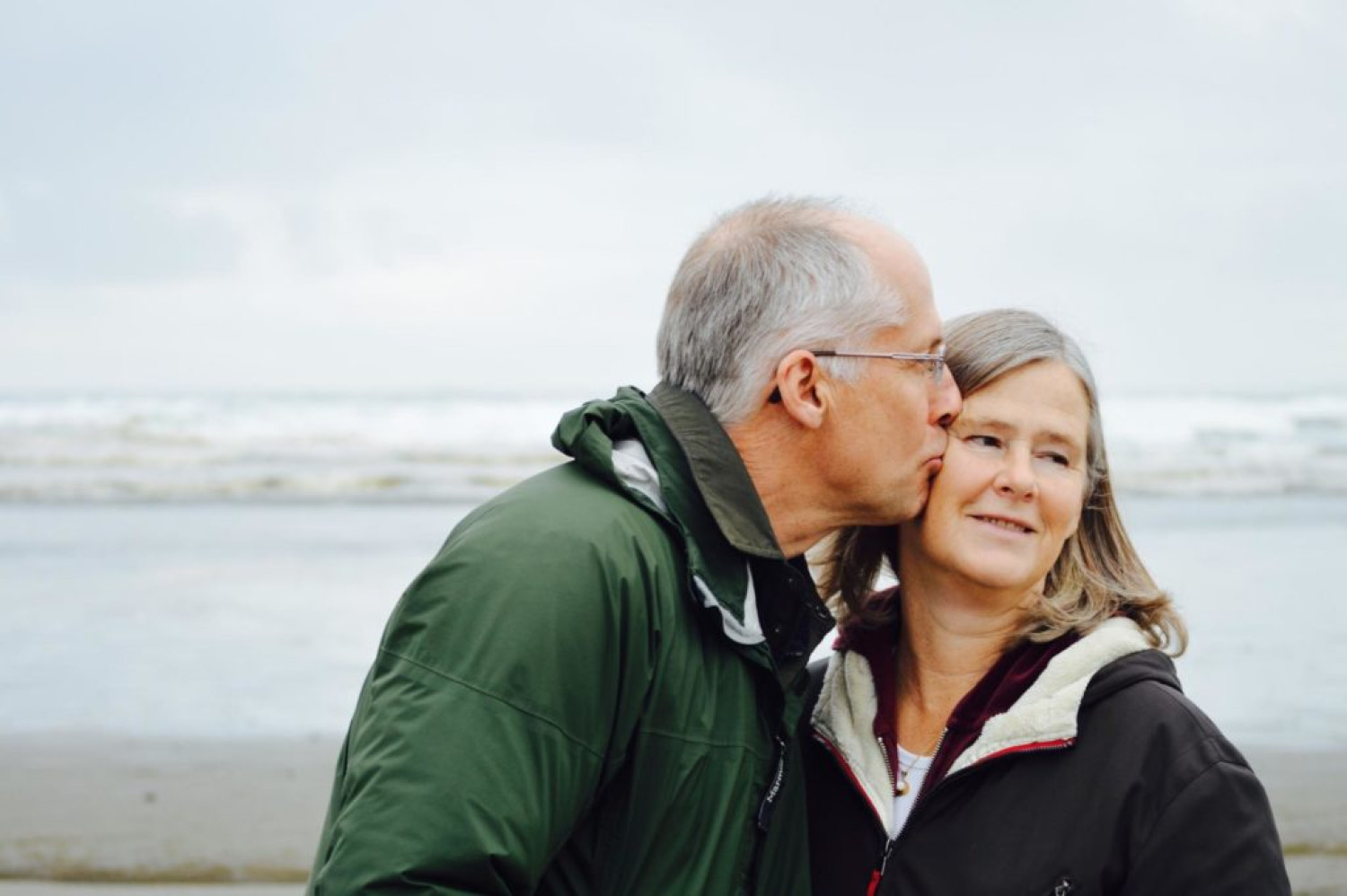 Happy older couple share a kiss on the beach. Dementia activities & Dementia Care - Focus Care